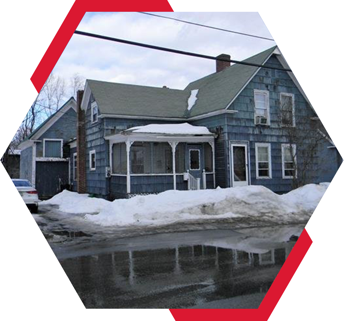 A house with snow on the ground and water in front of it.